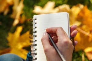 writing-in-notebook-making-list-with-fall-leaves-in-background