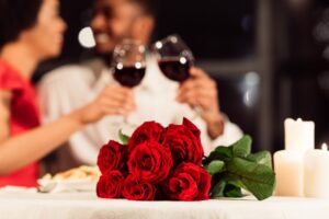 roses-on-table-with-couple-drinking-red-wine-in-background
